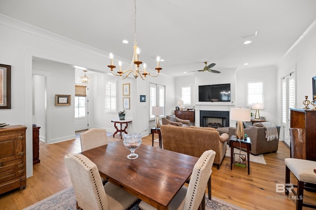 dining room featuring ceiling fan with notable chandelier, light hardwood / wood-style floors, and plenty of natural light