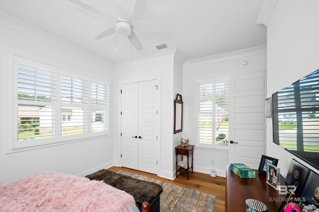 bedroom featuring multiple windows, ceiling fan, wood-type flooring, and ornamental molding