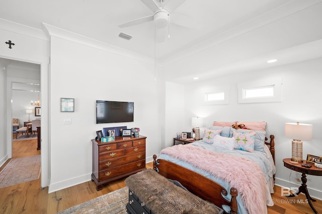 bedroom featuring ceiling fan with notable chandelier, light hardwood / wood-style floors, and ornamental molding