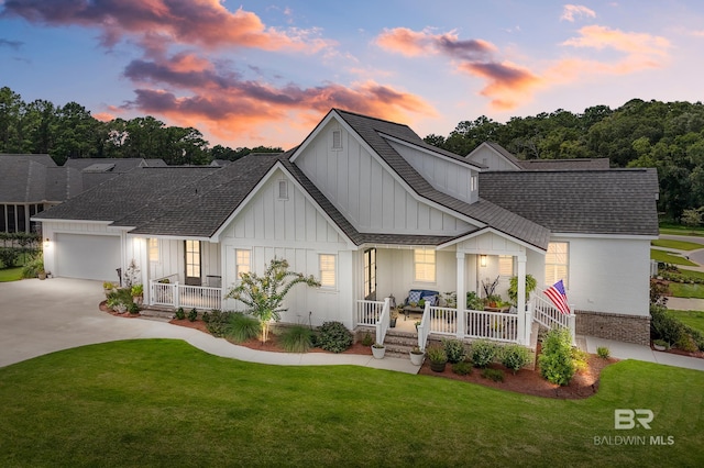 view of front of house featuring a lawn, board and batten siding, covered porch, concrete driveway, and roof with shingles