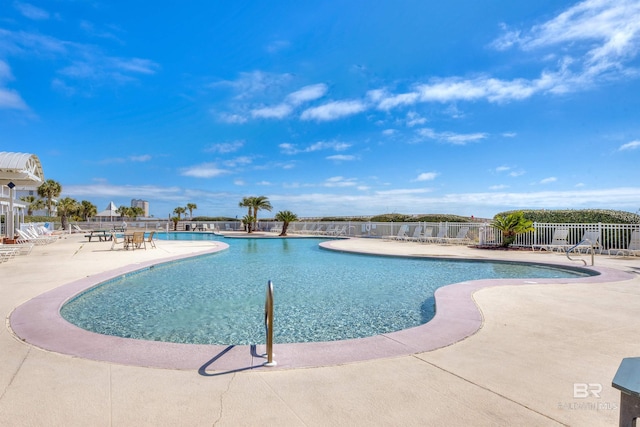 community pool with fence and a patio area
