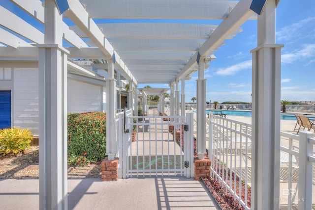 view of patio / terrace featuring a community pool, a gate, and a pergola