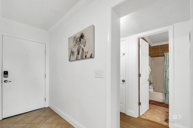 entryway featuring light tile patterned flooring, baseboards, and ornamental molding