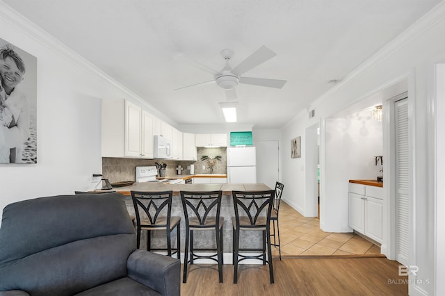 kitchen featuring open floor plan, tasteful backsplash, white appliances, ceiling fan, and a peninsula