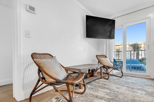 living area featuring baseboards, ornamental molding, and wood finished floors