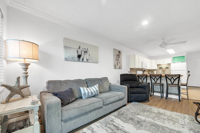 living area with ceiling fan, crown molding, and light wood-type flooring