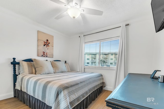 bedroom featuring baseboards, crown molding, light wood-style flooring, and a textured ceiling