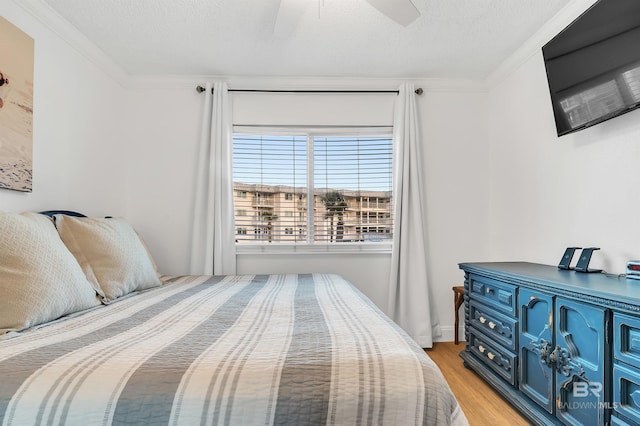 bedroom featuring crown molding, light wood-style floors, ceiling fan, and a textured ceiling