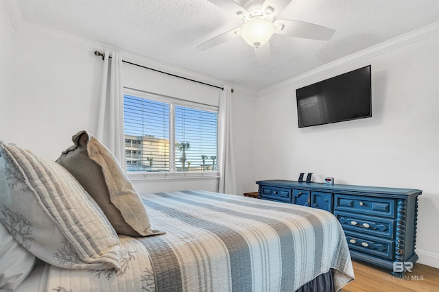 bedroom with a ceiling fan, ornamental molding, a textured ceiling, and light wood-type flooring