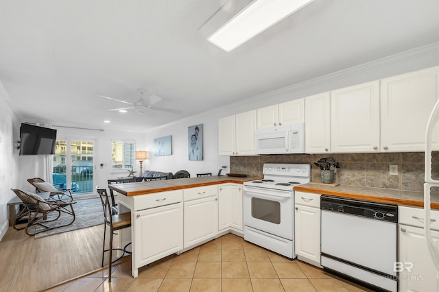kitchen featuring white cabinets, tile counters, a peninsula, and white appliances