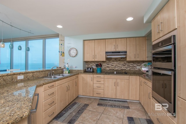 kitchen featuring a water view, sink, light brown cabinets, and stainless steel double oven