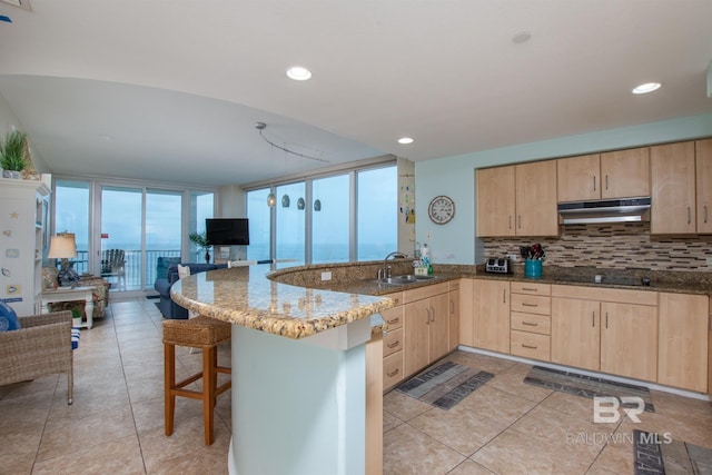 kitchen featuring stone counters, sink, light brown cabinets, and kitchen peninsula
