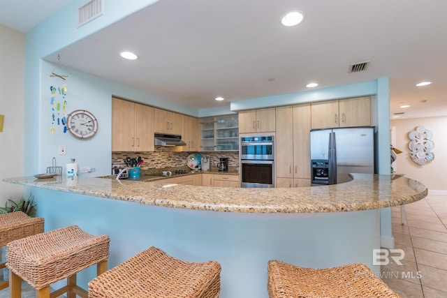kitchen with tasteful backsplash, stainless steel appliances, kitchen peninsula, and light brown cabinets