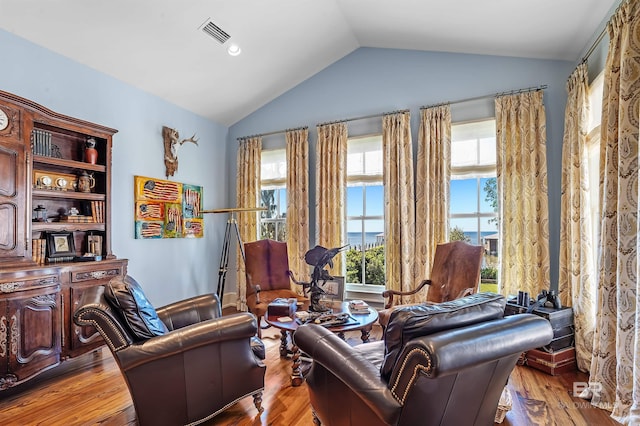 living area with vaulted ceiling, wood finished floors, and visible vents