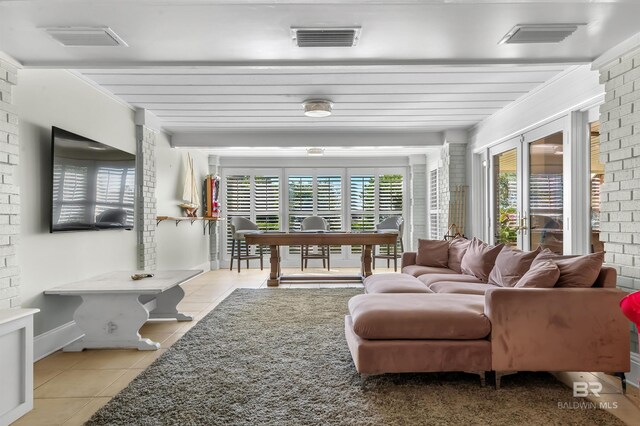 living room with brick wall, light tile patterned flooring, and visible vents