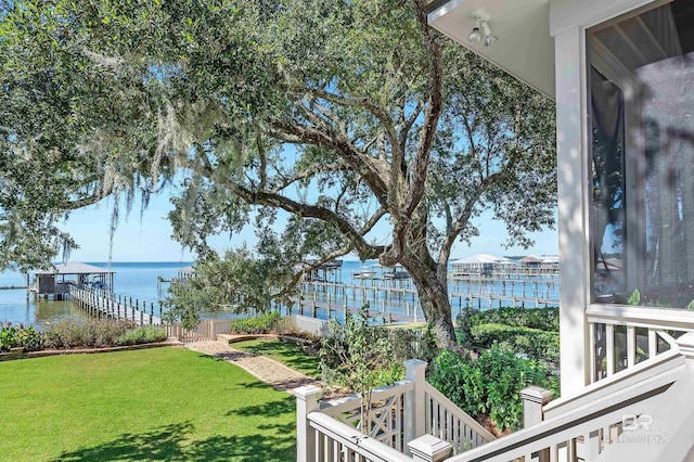 view of yard featuring a water view, a boat dock, and fence