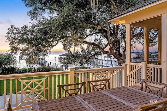 wooden deck featuring a water view, outdoor dining area, and a yard