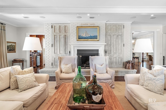 living area featuring a fireplace with raised hearth, visible vents, ornamental molding, brick wall, and wood finished floors