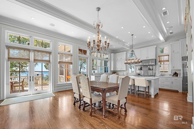 dining room featuring visible vents, ornamental molding, wood finished floors, a notable chandelier, and a wealth of natural light