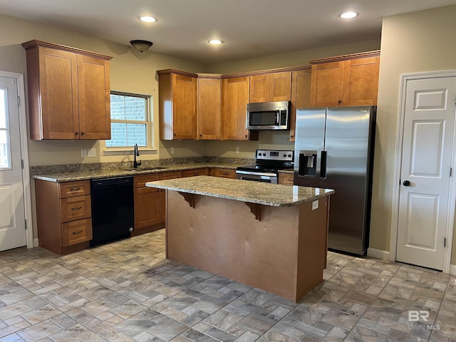 kitchen featuring a breakfast bar, sink, a center island, appliances with stainless steel finishes, and light stone countertops