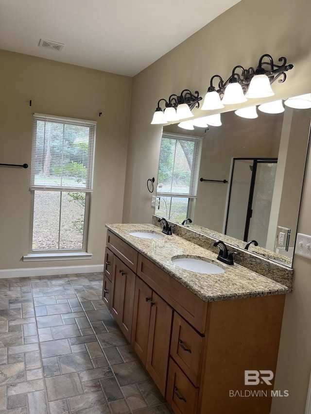 bathroom with plenty of natural light, a shower with door, and vanity