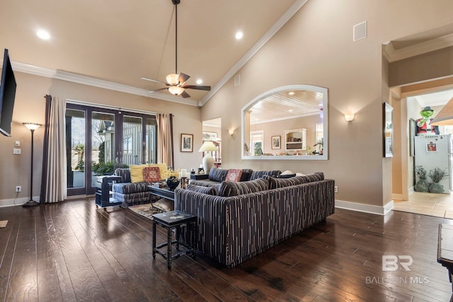 living room featuring a towering ceiling, ornamental molding, ceiling fan, dark wood-type flooring, and french doors