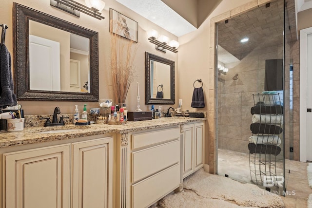 bathroom featuring double vanity, a stall shower, and a sink