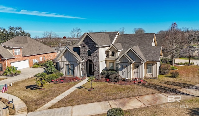 view of front of property featuring board and batten siding, a shingled roof, a front lawn, stone siding, and driveway