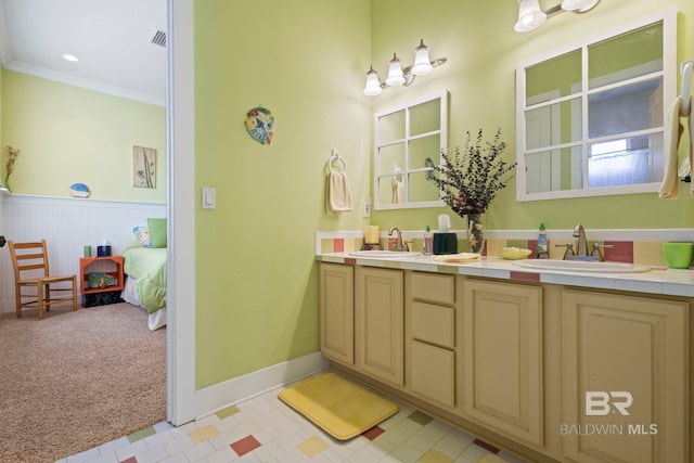 bathroom featuring a sink, visible vents, ornamental molding, and double vanity