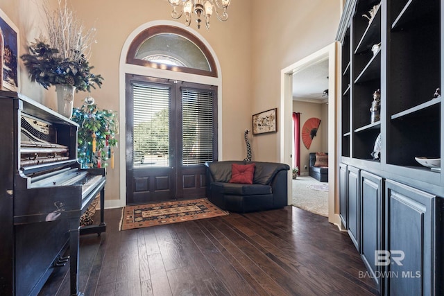 entrance foyer featuring dark wood-type flooring, crown molding, and a notable chandelier