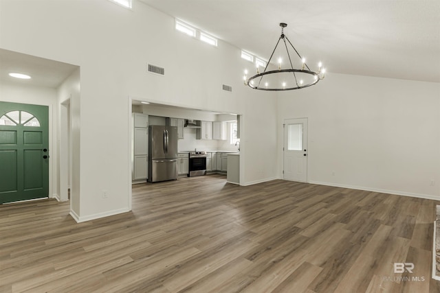 unfurnished living room with baseboards, visible vents, and wood finished floors
