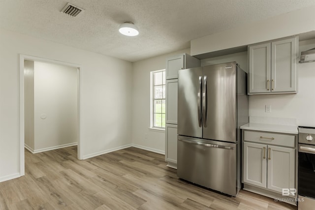 kitchen featuring appliances with stainless steel finishes, light wood-style floors, and gray cabinetry