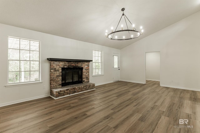 unfurnished living room featuring a wealth of natural light, lofted ceiling, a fireplace, and wood finished floors