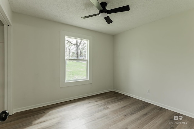 unfurnished room with a textured ceiling, ceiling fan, wood finished floors, and baseboards