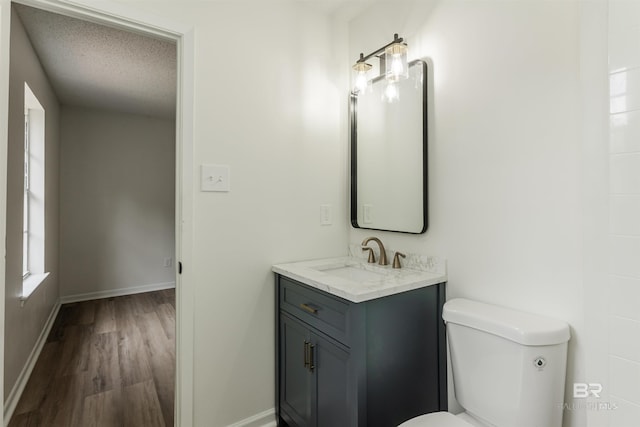 bathroom with baseboards, toilet, wood finished floors, a textured ceiling, and vanity