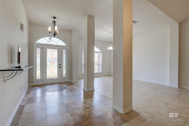 foyer with a chandelier, a textured ceiling, and light tile patterned floors