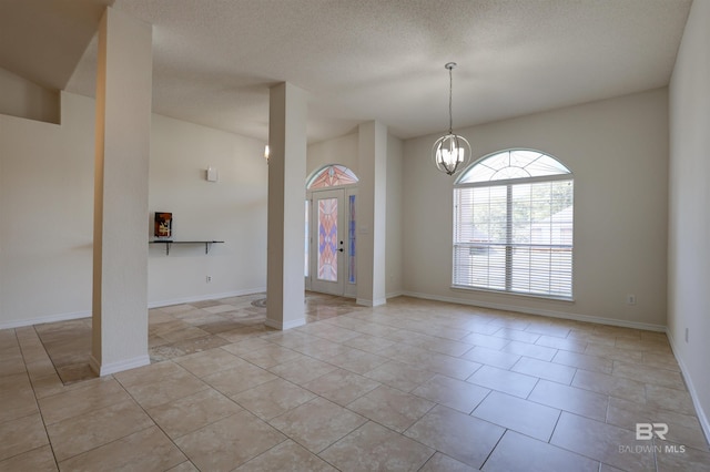 empty room with light tile patterned flooring, a chandelier, and a textured ceiling