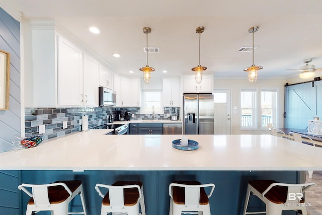 kitchen featuring a breakfast bar area, backsplash, visible vents, and appliances with stainless steel finishes