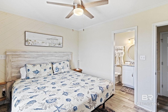 bedroom featuring light wood-type flooring, a ceiling fan, ensuite bath, and crown molding