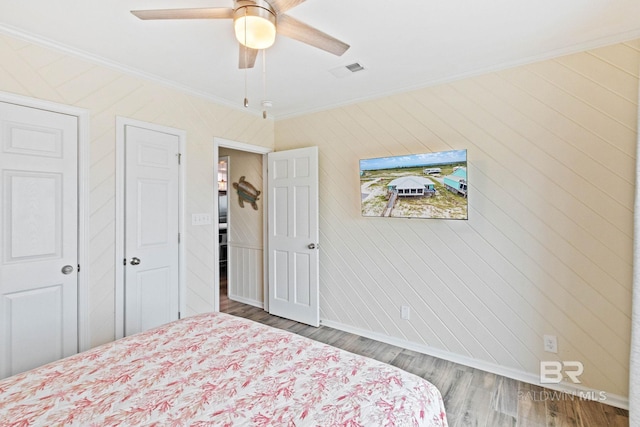 unfurnished bedroom with a ceiling fan, wood finished floors, visible vents, baseboards, and crown molding