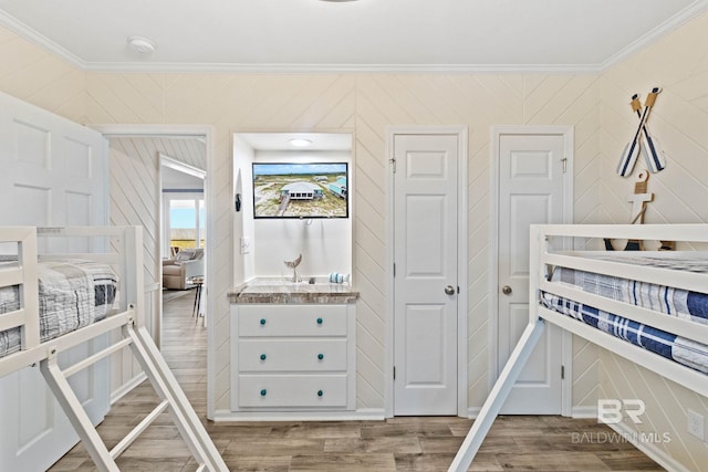 bedroom with wood finished floors and crown molding