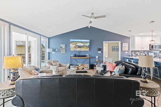 living area featuring lofted ceiling, wood finished floors, a ceiling fan, and visible vents