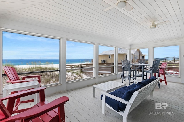 sunroom featuring a wealth of natural light, a water view, ceiling fan, and vaulted ceiling