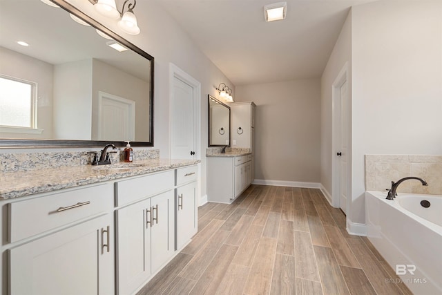 33861 Rutland Ln, Spanish Fort, AL 36527 - bathroom with two vanities, a bath, wood finished floors, and baseboards
