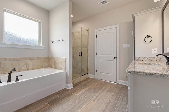 33861 Rutland Ln, Spanish Fort, AL 36527 - bathroom with vanity, a shower stall, a garden tub, wood finished floors, and baseboards