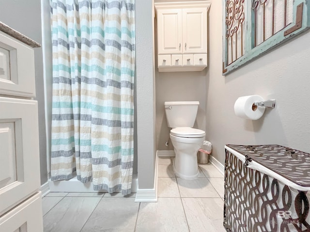 bathroom featuring tile patterned floors, shower / bath combo with shower curtain, and toilet