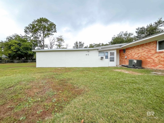 back of property featuring a lawn and central AC