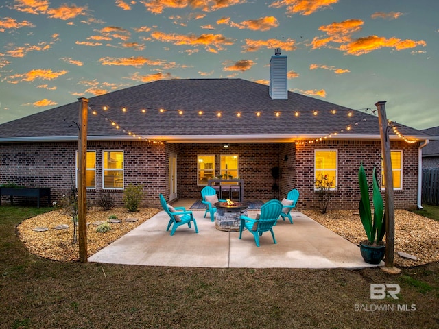 back house at dusk featuring a fire pit and a patio