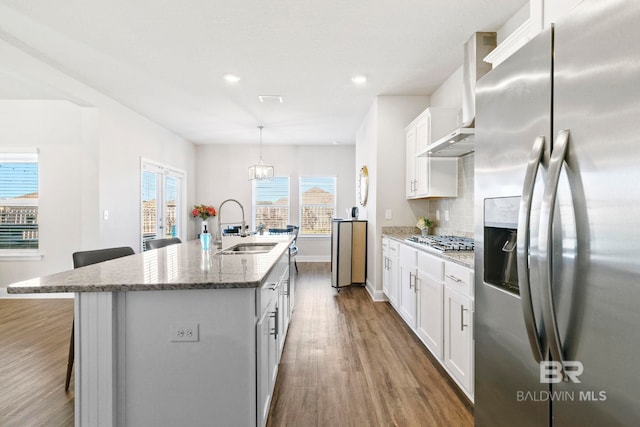 kitchen featuring a center island with sink, sink, tasteful backsplash, white cabinetry, and stainless steel appliances