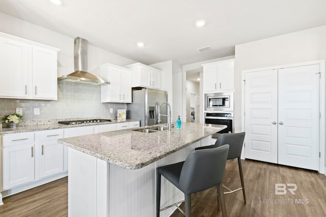 kitchen with appliances with stainless steel finishes, white cabinetry, and wall chimney exhaust hood